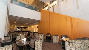 Un hall de hotel con varias zonas de estar, un bar y una escalera que sube a un nivel superior.