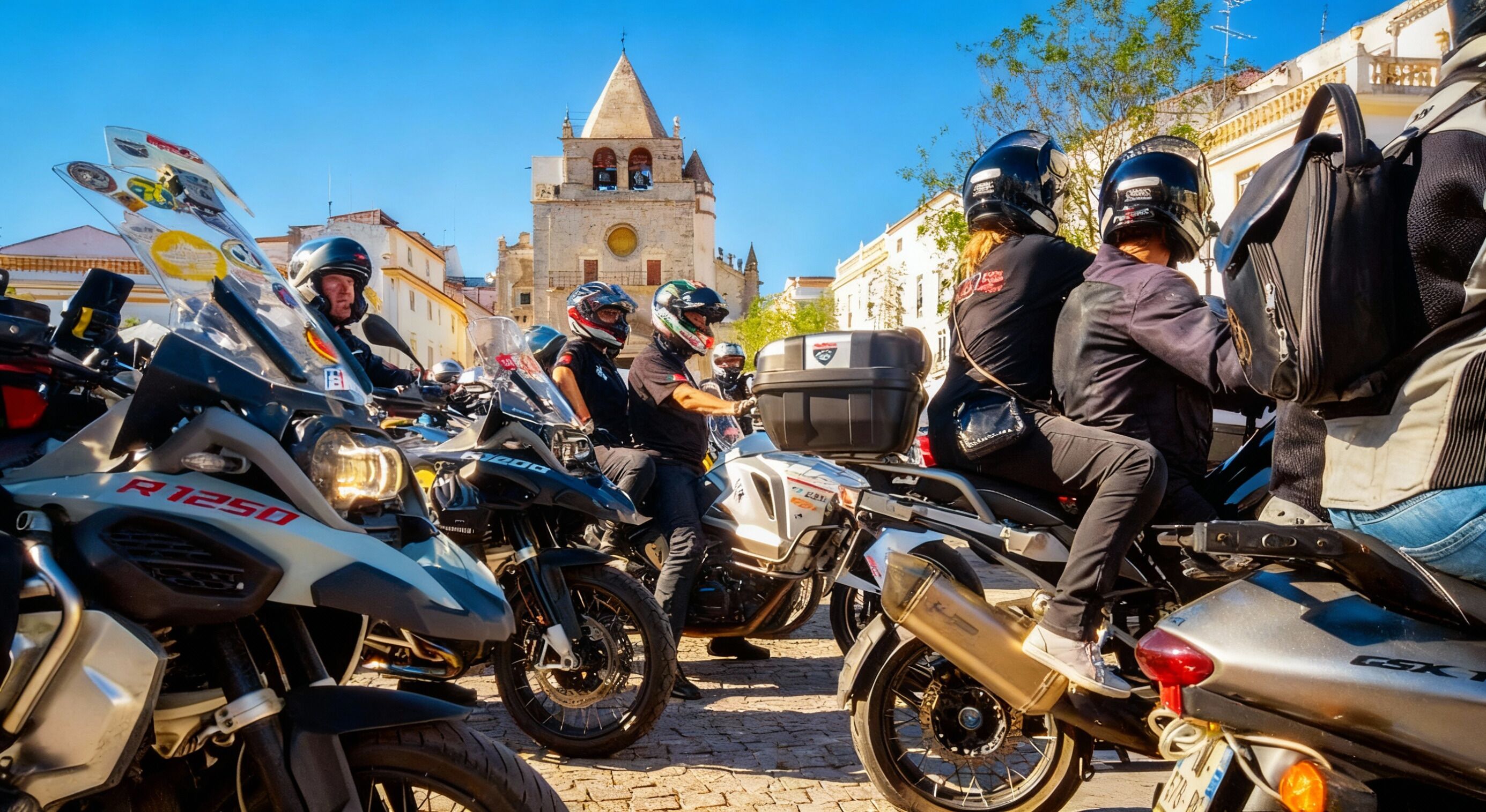 A group of motorcyclists parked in front of a historic building with a bell tower.