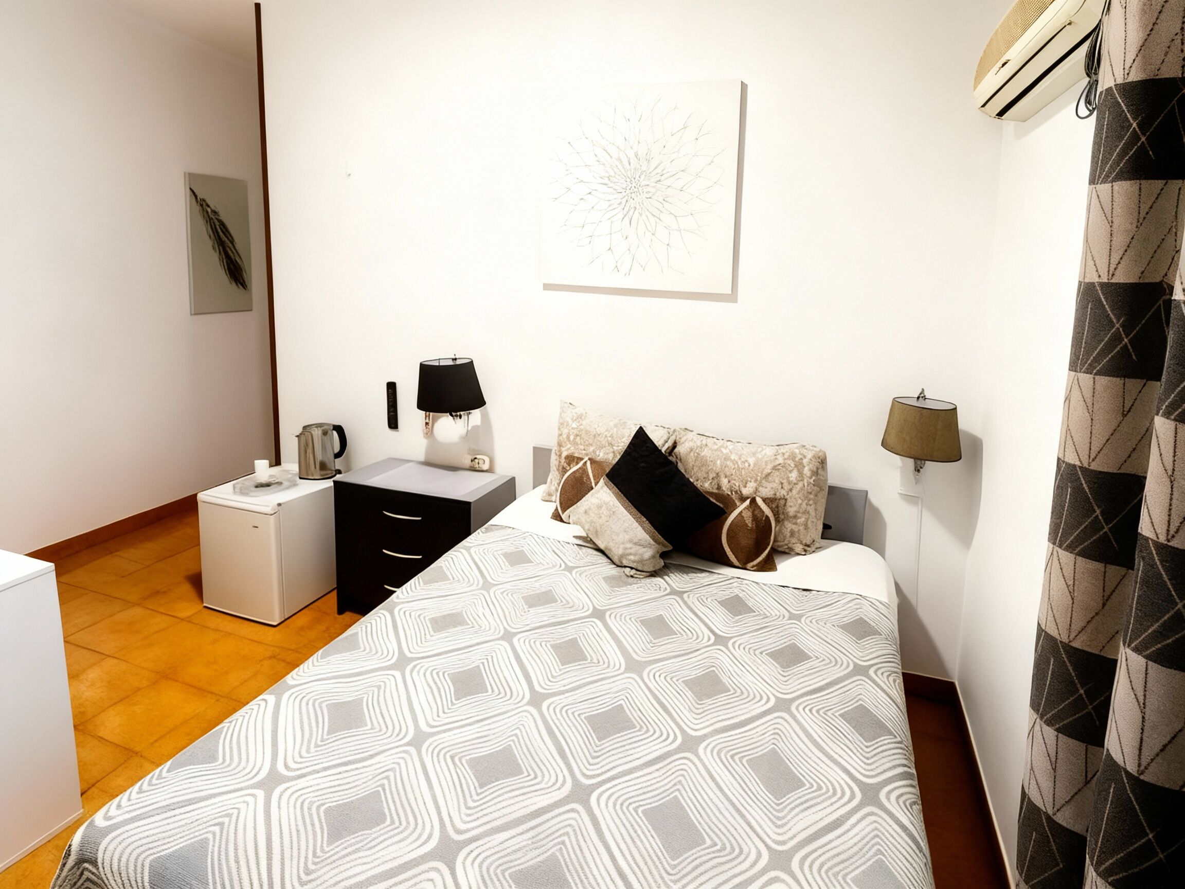 Un dormitorio con cama, mesita de noche, lámpara, reloj de pared y radiador.