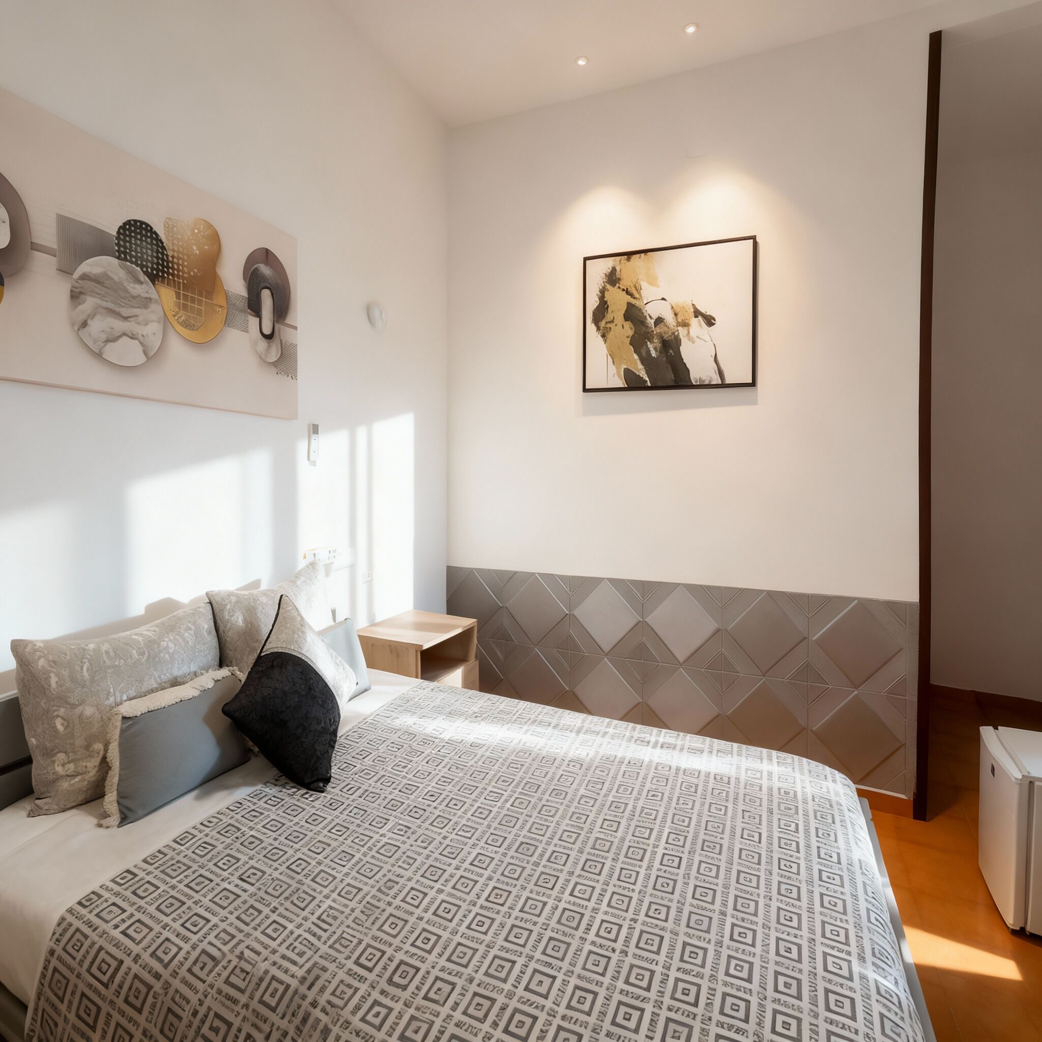 Un dormitorio moderno con una cama grande, una mesita de noche, una obra de arte colgada en la pared y un cabecero con estampado geométrico.