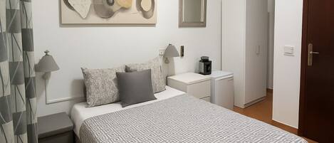 A bedroom with a bed, bedside tables, a wardrobe, a painting, and a mirror.
