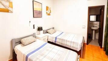 A bedroom with two beds, a nightstand, a lamp, and a painting on the wall.