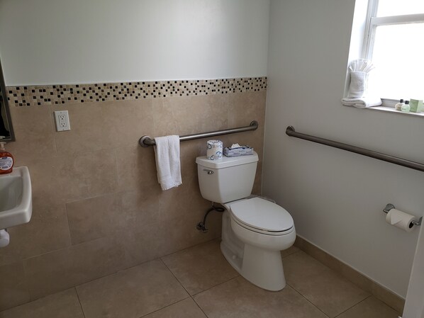 Un baño con inodoro, baranda, toalla y ventana.