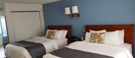 A hotel room with two beds, a blue wall, and a white ceiling.
