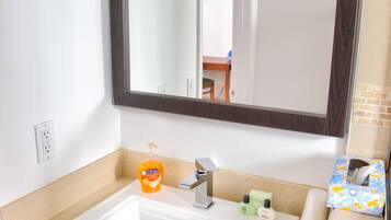 A bathroom with a white sink, dark wooden cabinet, and a large mirror above the sink.