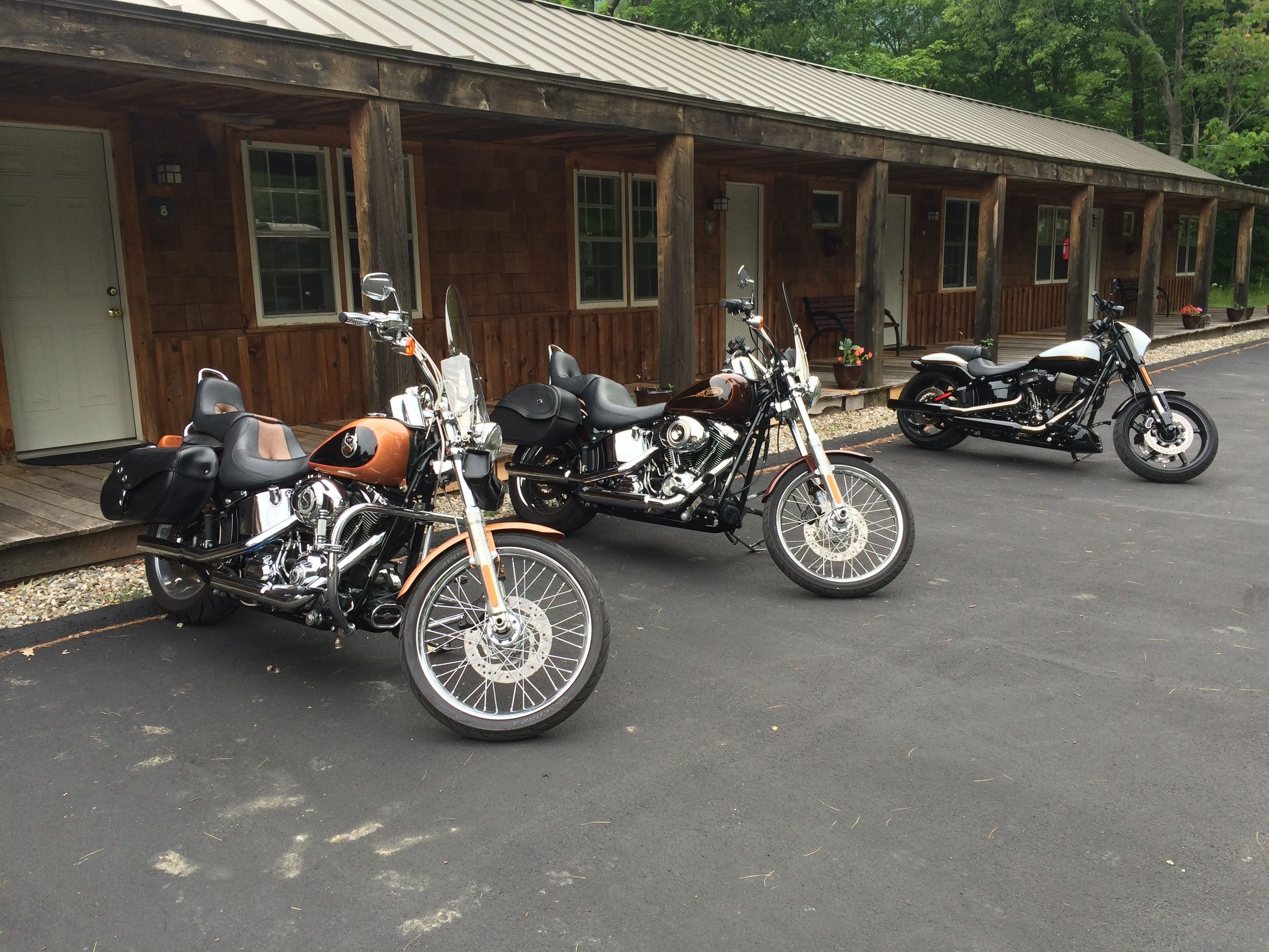 A row of motorcycles parked in front of a wooden building with multiple doors.