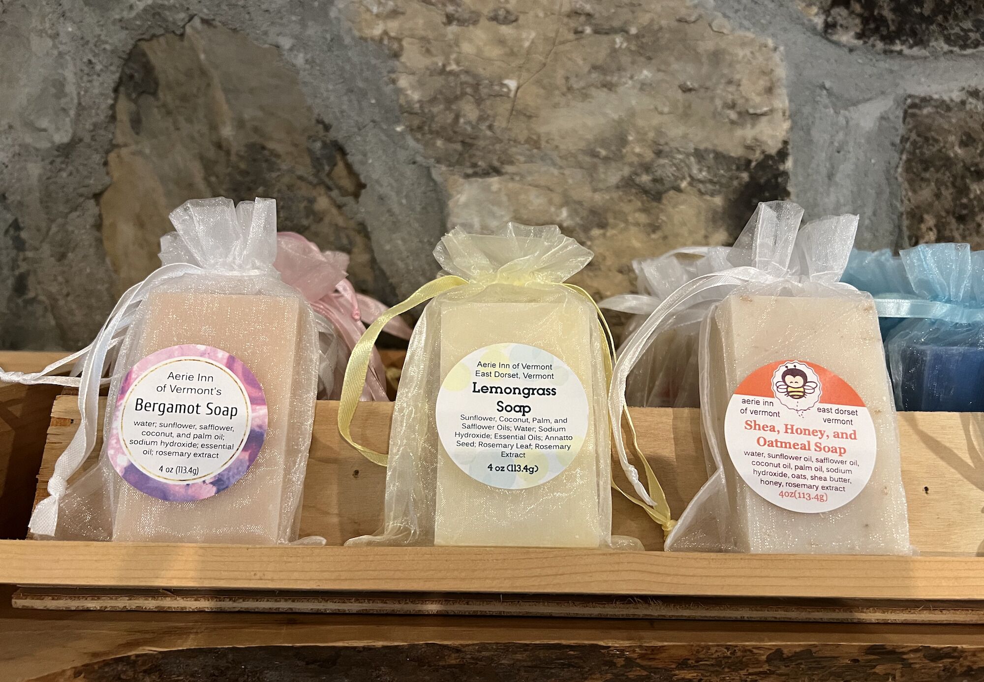 Three soap bars on a wooden shelf.