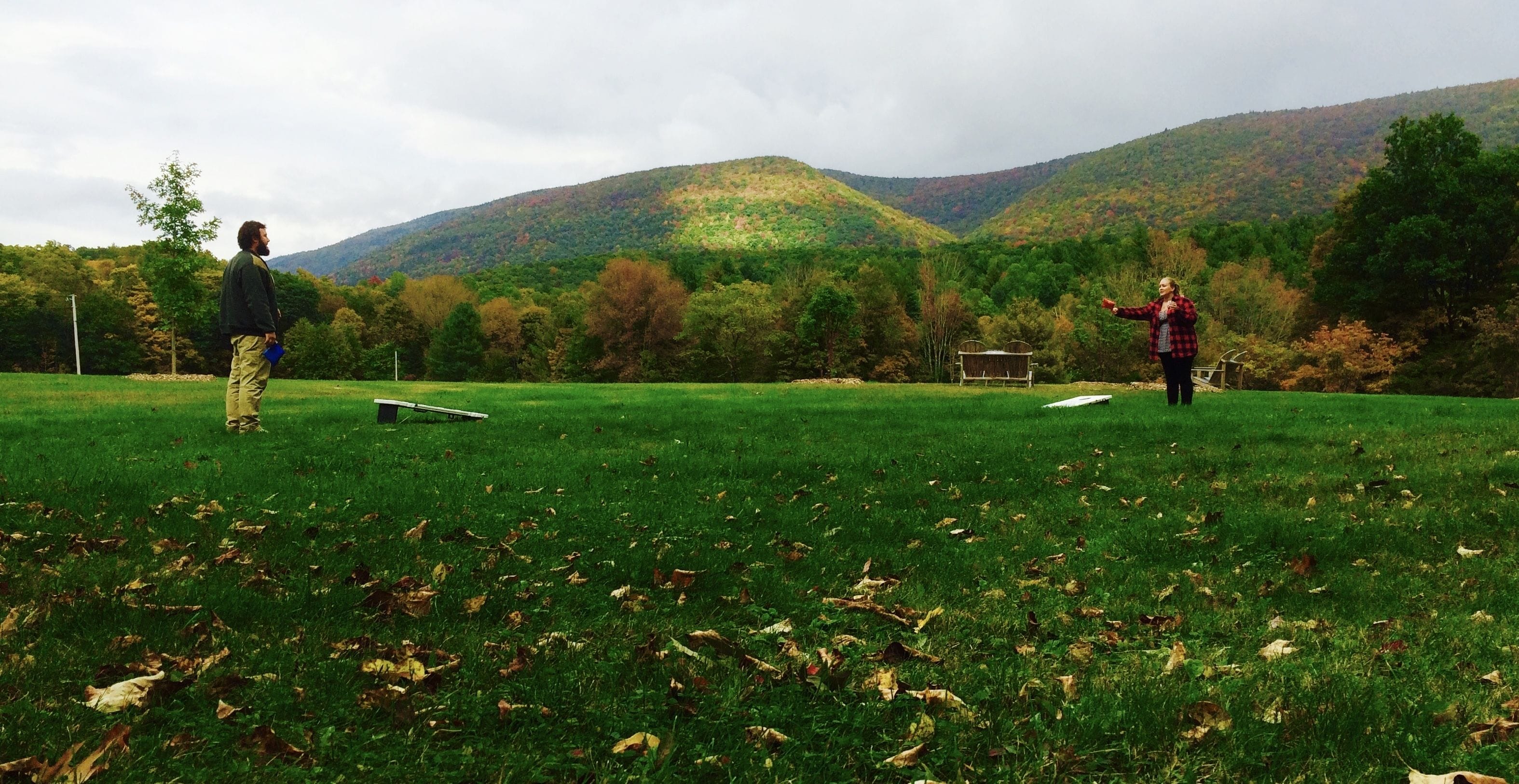 Um campo gramado com um banco e uma mesa, cercado por árvores e colinas.
