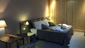 Habitación de hotel con cama, lámparas de noche, mesita de noche, una pequeña mesa y un panel de pared de madera.
