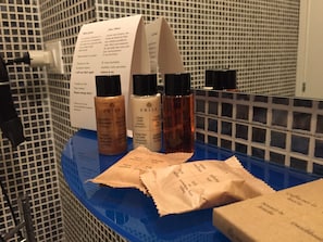 Une salle de bain avec un comptoir bleu sur lequel sont disposés divers produits de toilette et un distributeur de serviettes en papier.