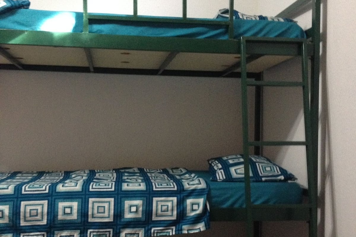 A bunk bed with patterned bedding in a room with plain walls.