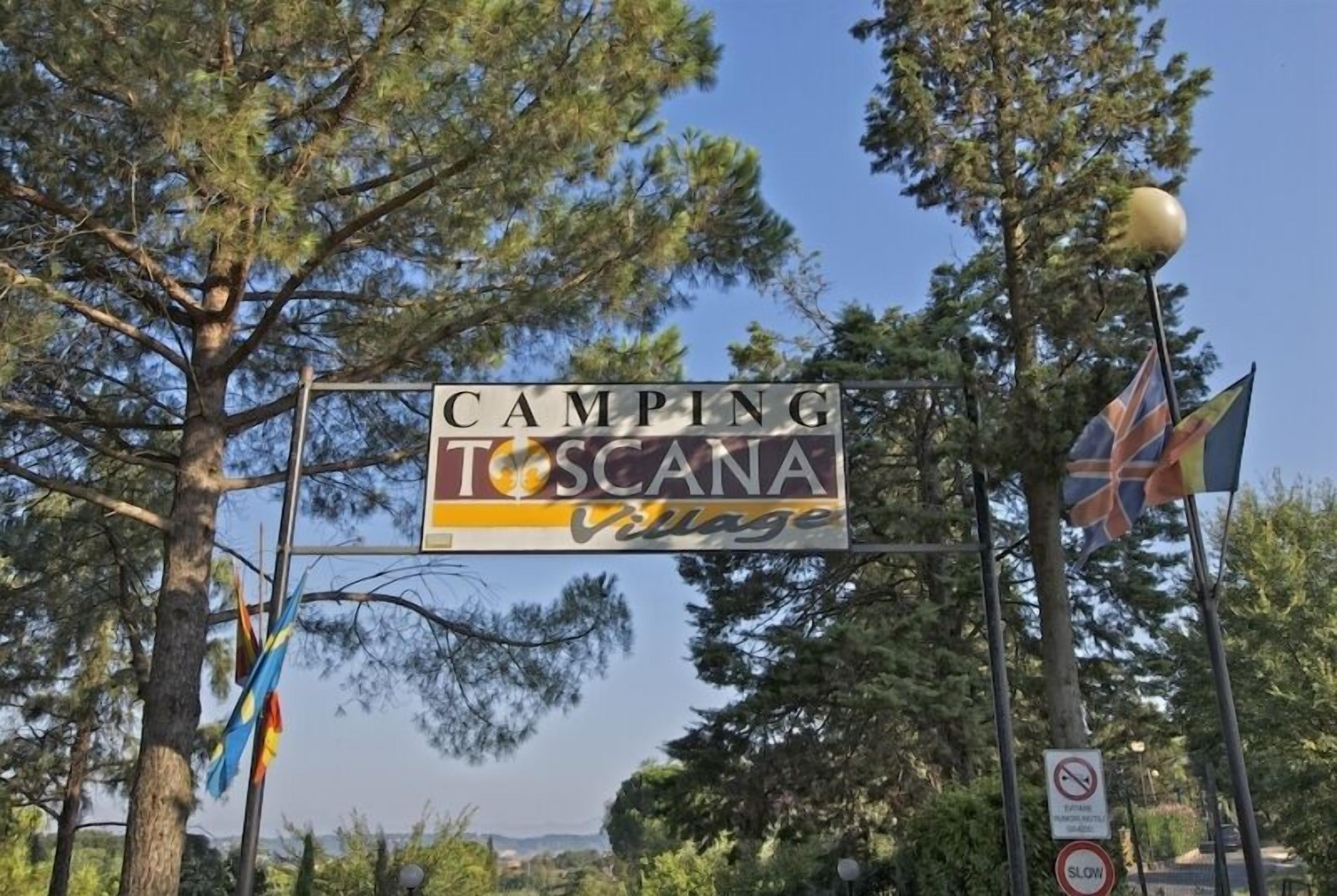 Schild für Camping Toscana Village mit einem Verbotsschild für Rauchen und einer Geschwindigkeitsbegrenzung darunter.