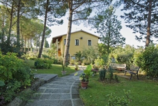 A yellow building with a stone pathway leading to a bench. - Toscana Holiday Village (Montopoli in Val d'Arno)