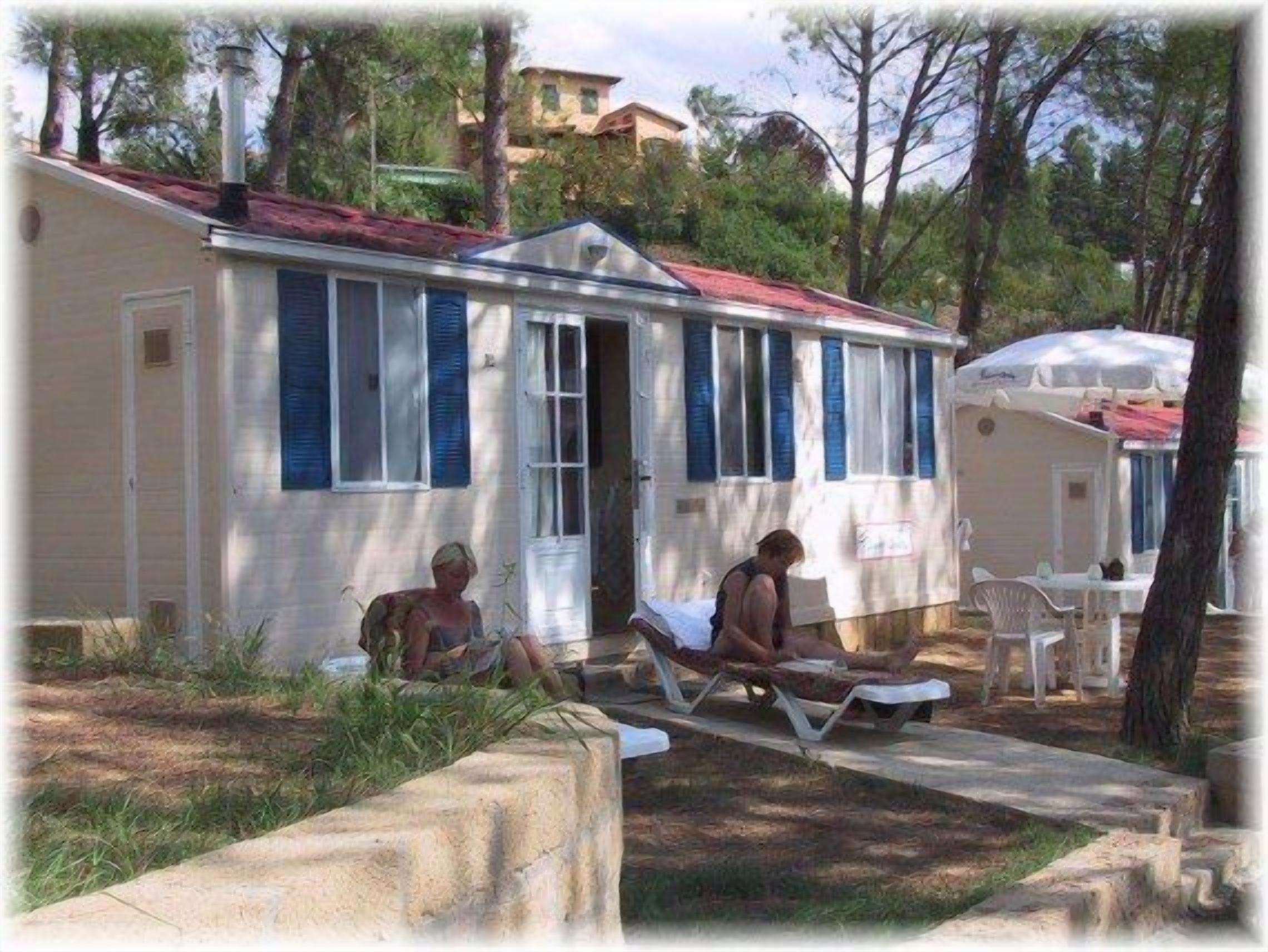 A row of mobile homes with a central building, each with a window and a door.