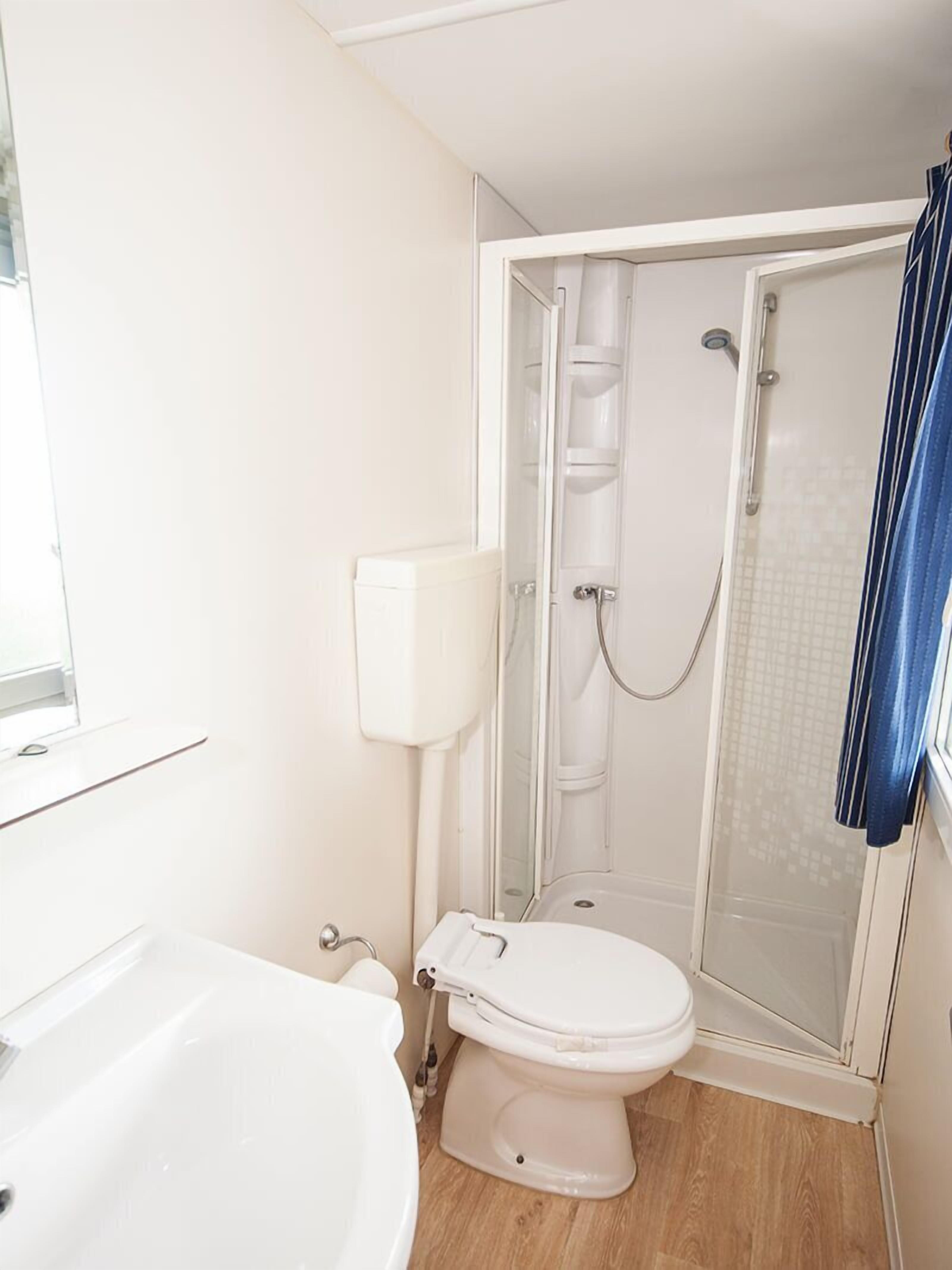 Un baño pequeño y funcional con inodoro, cabina de ducha y lavamanos.