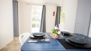 Una mesa de comedor dispuesta con platos, cubiertos y vasos, con un pequeño jarrón de flores y un extintor en la pared.