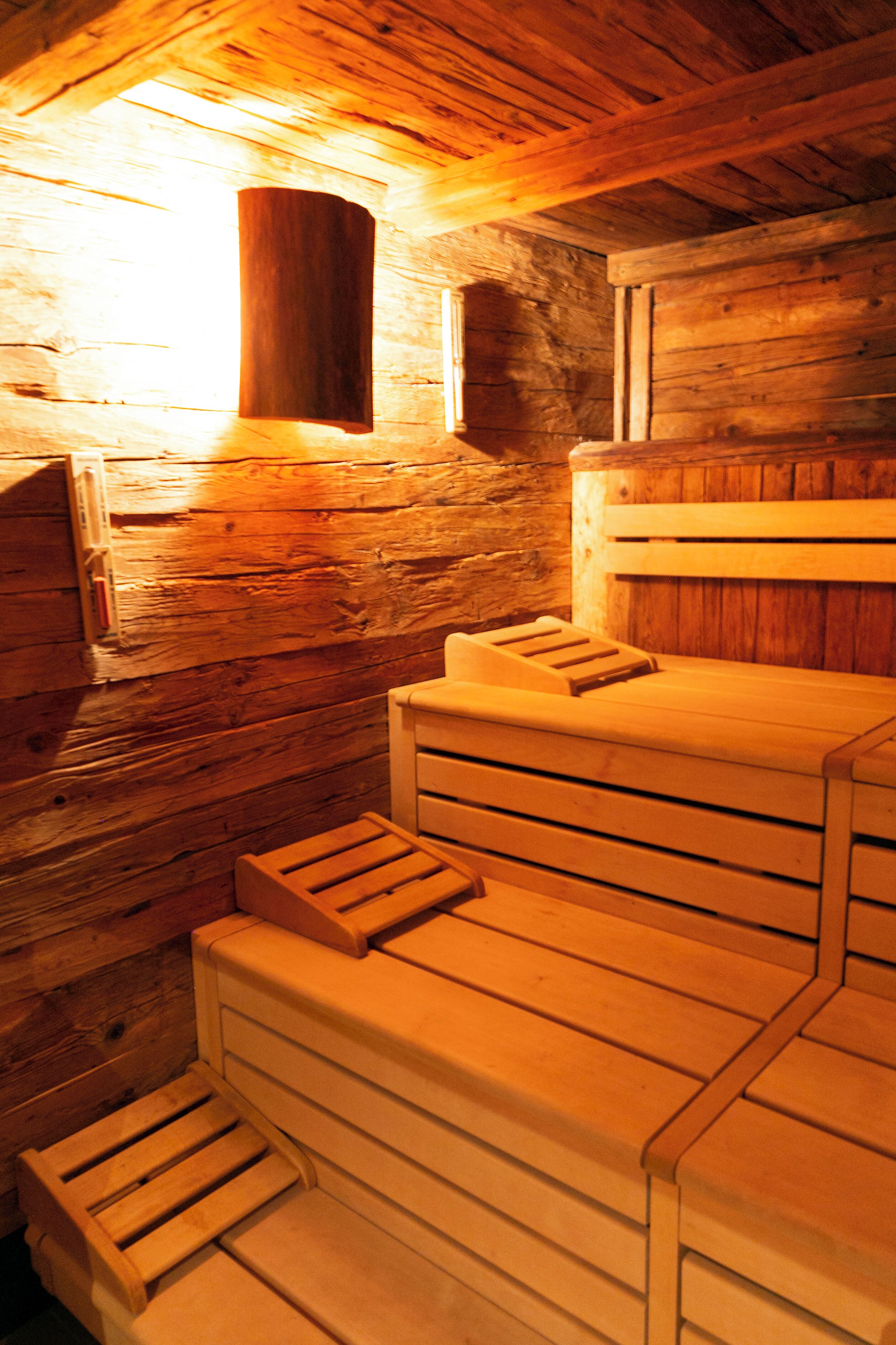 A sauna with wooden benches and a wooden wall.