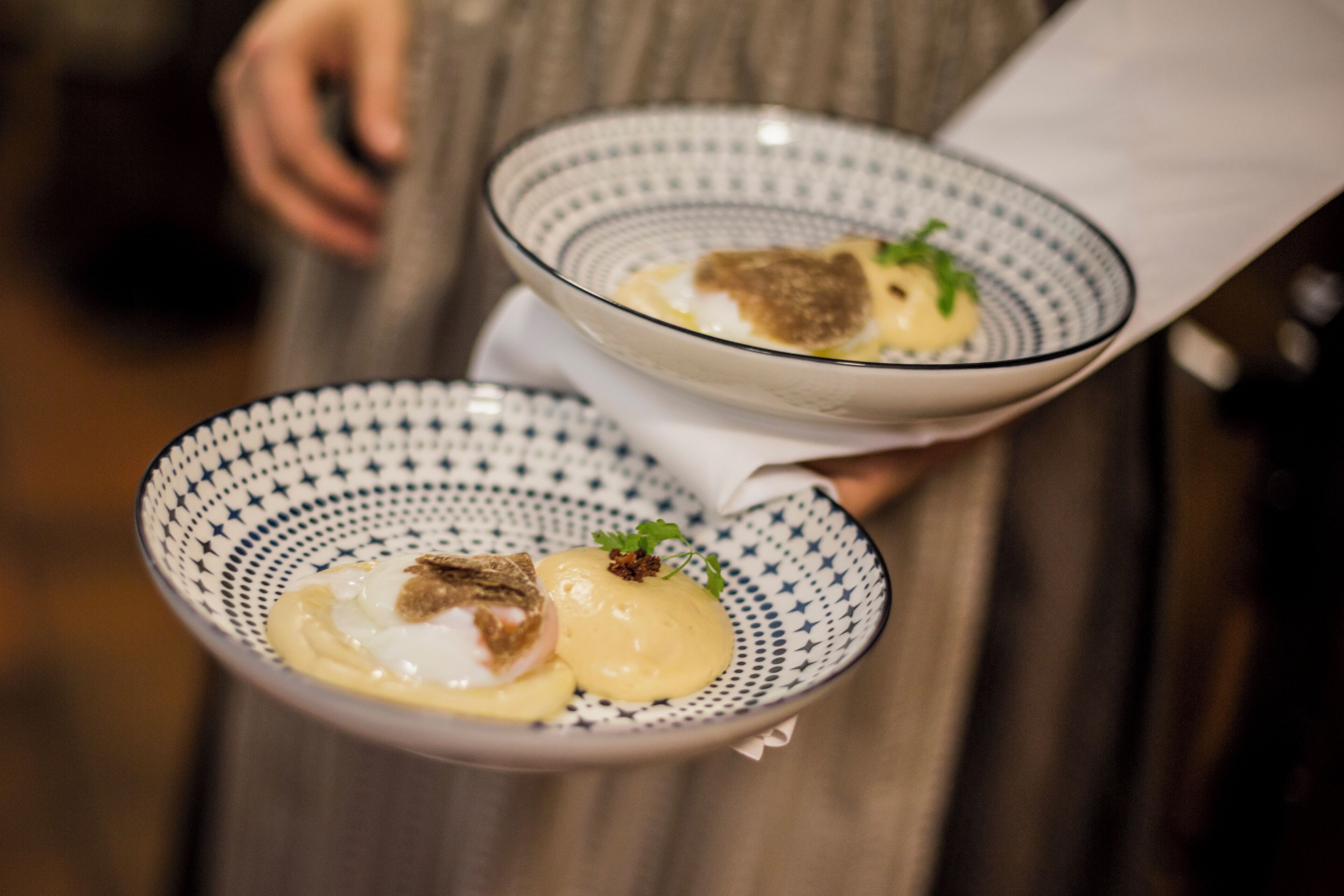 Two bowls of food with a patterned design, held by a person.