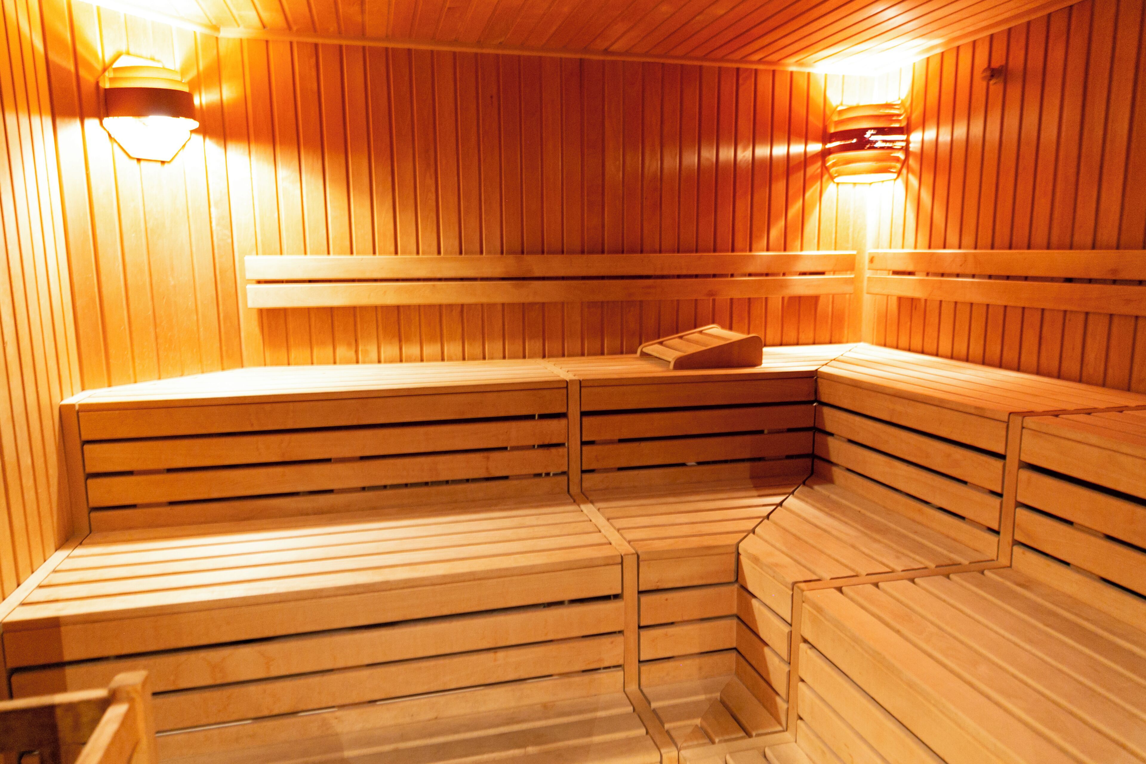 A sauna with wooden benches and benches, arranged in a corner with a sloped ceiling.