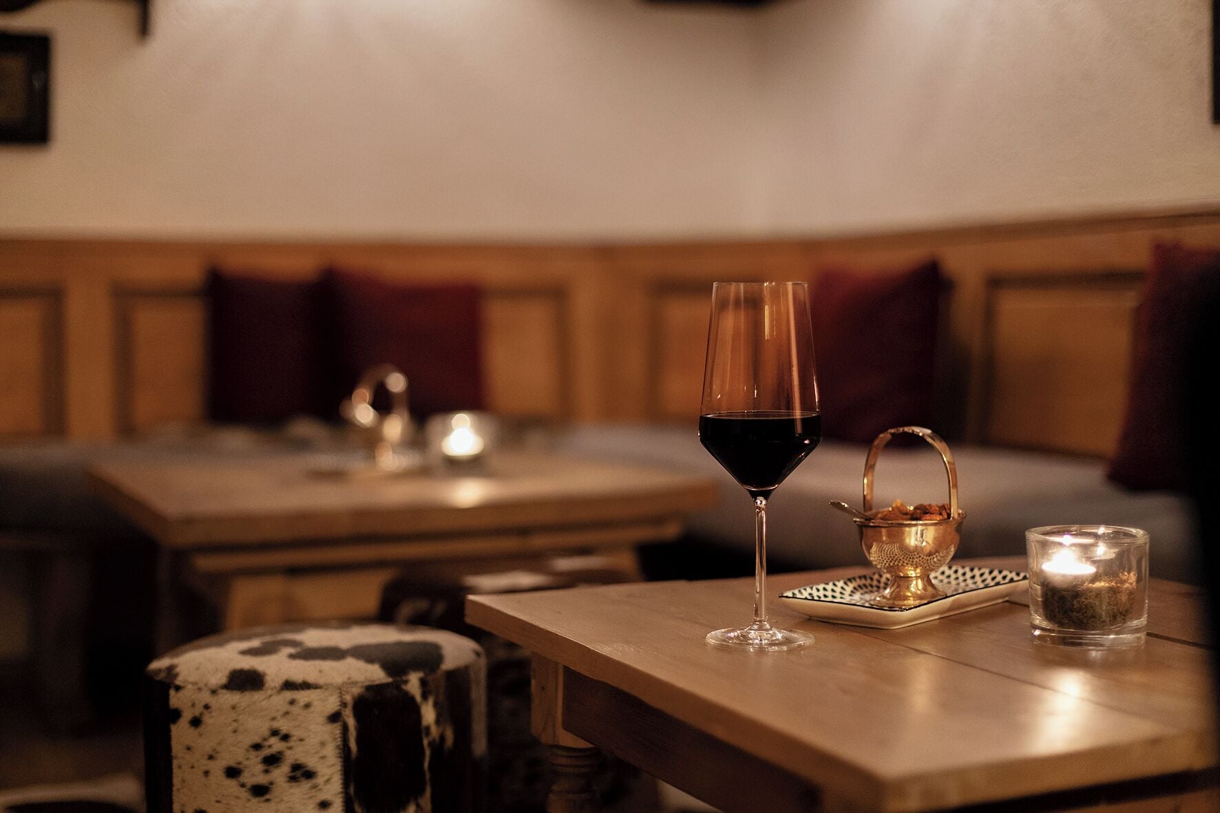 Une table à manger avec un verre à vin et une bougie, un chandelier et un chemin de table à motifs.