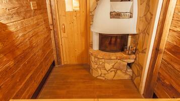 A wooden interior with a stone fireplace, wooden walls, and a tiled floor.