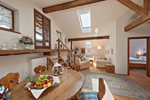 A spacious living area with a wooden dining table, a staircase, and a cozy seating area. - Landgasthof Karner (Frasdorf)