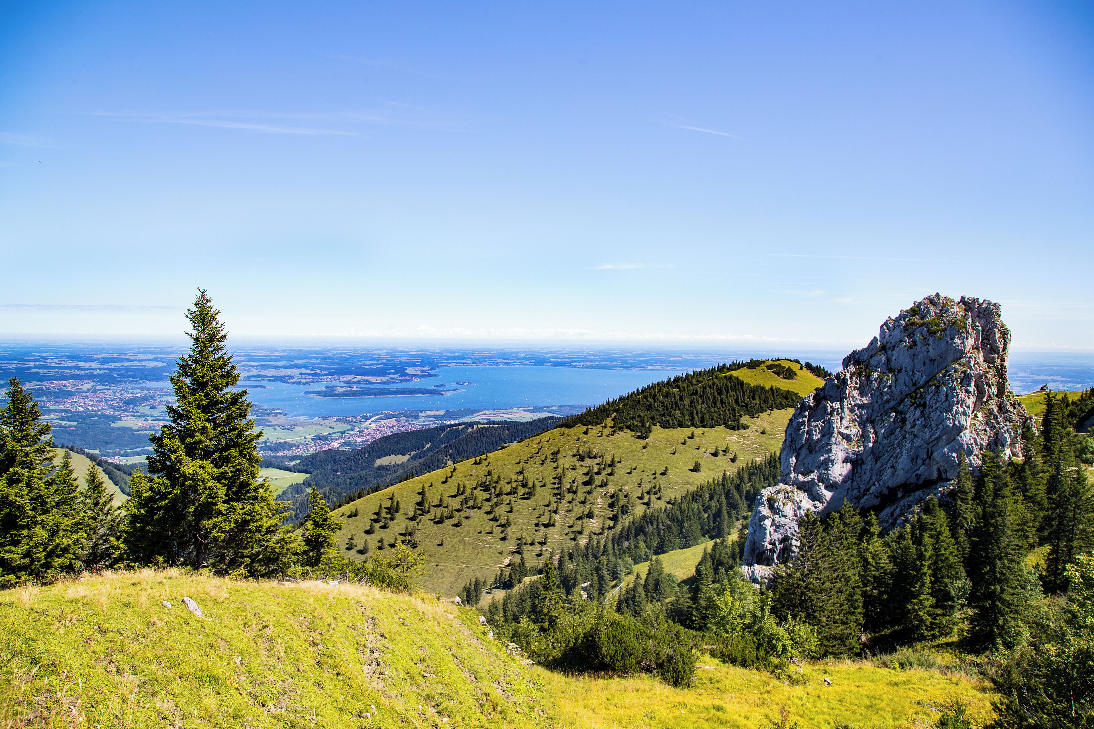 A mountainous landscape with a prominent rocky outcrop and a view of a distant body of water.