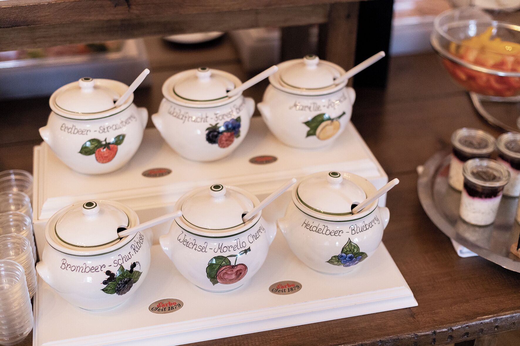 A table with six white ceramic jars labeled with different types of beer and their corresponding fruit flavors, each with a white spoon.