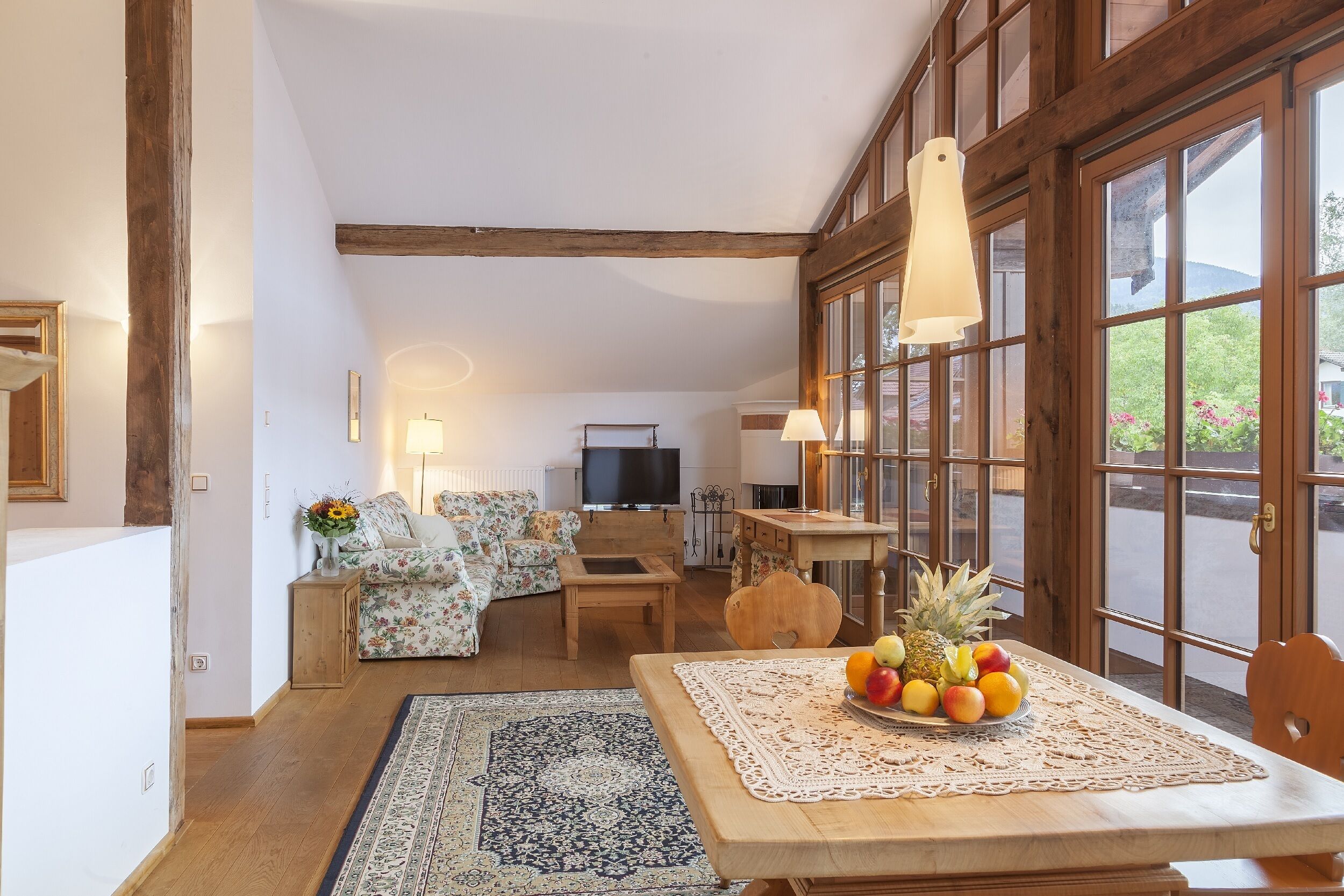 A cozy living room with a sofa, a wooden table with fruit, and a television.
