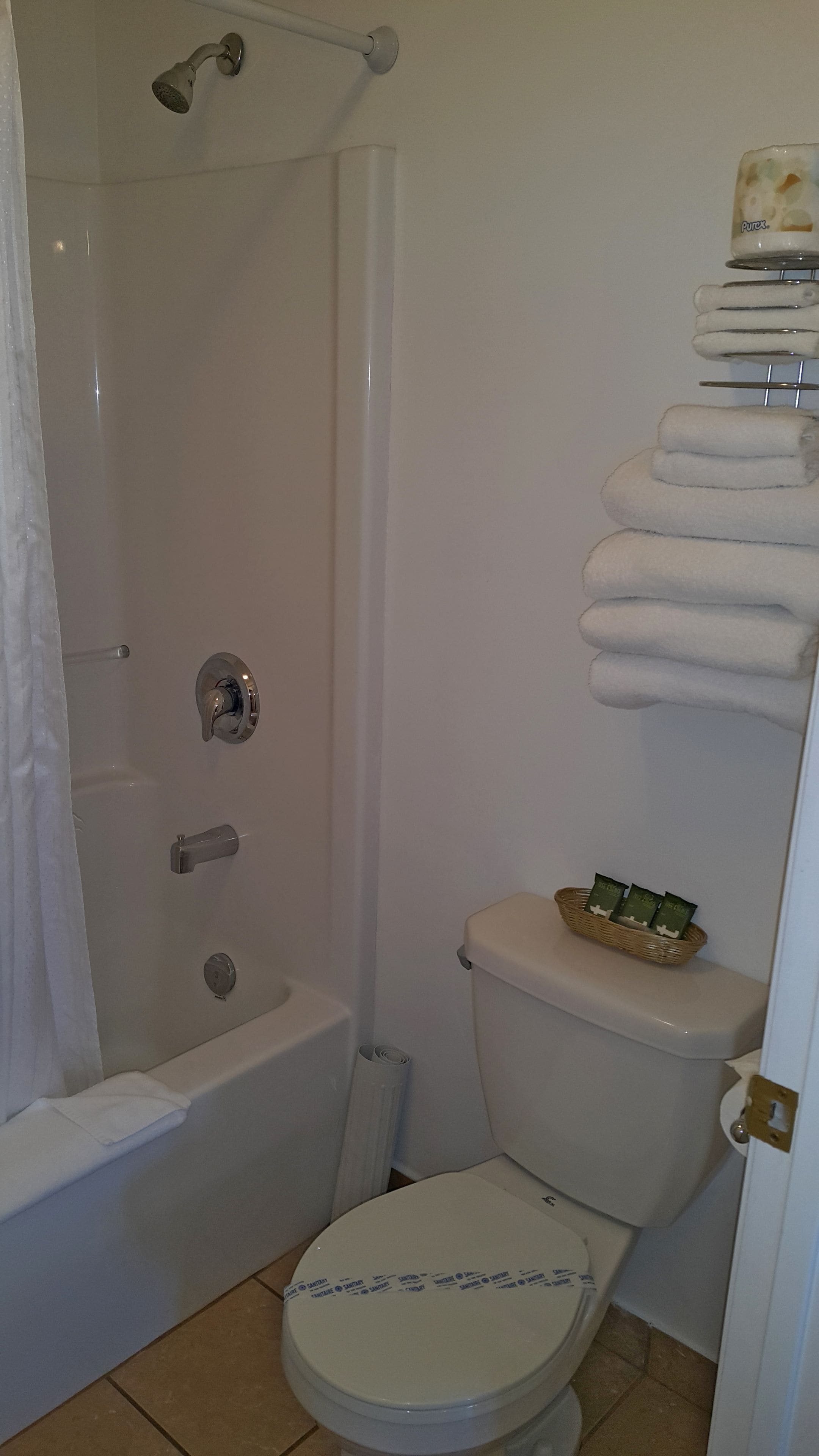 A bathroom with a bathtub, toilet, and a shelf with towels.
