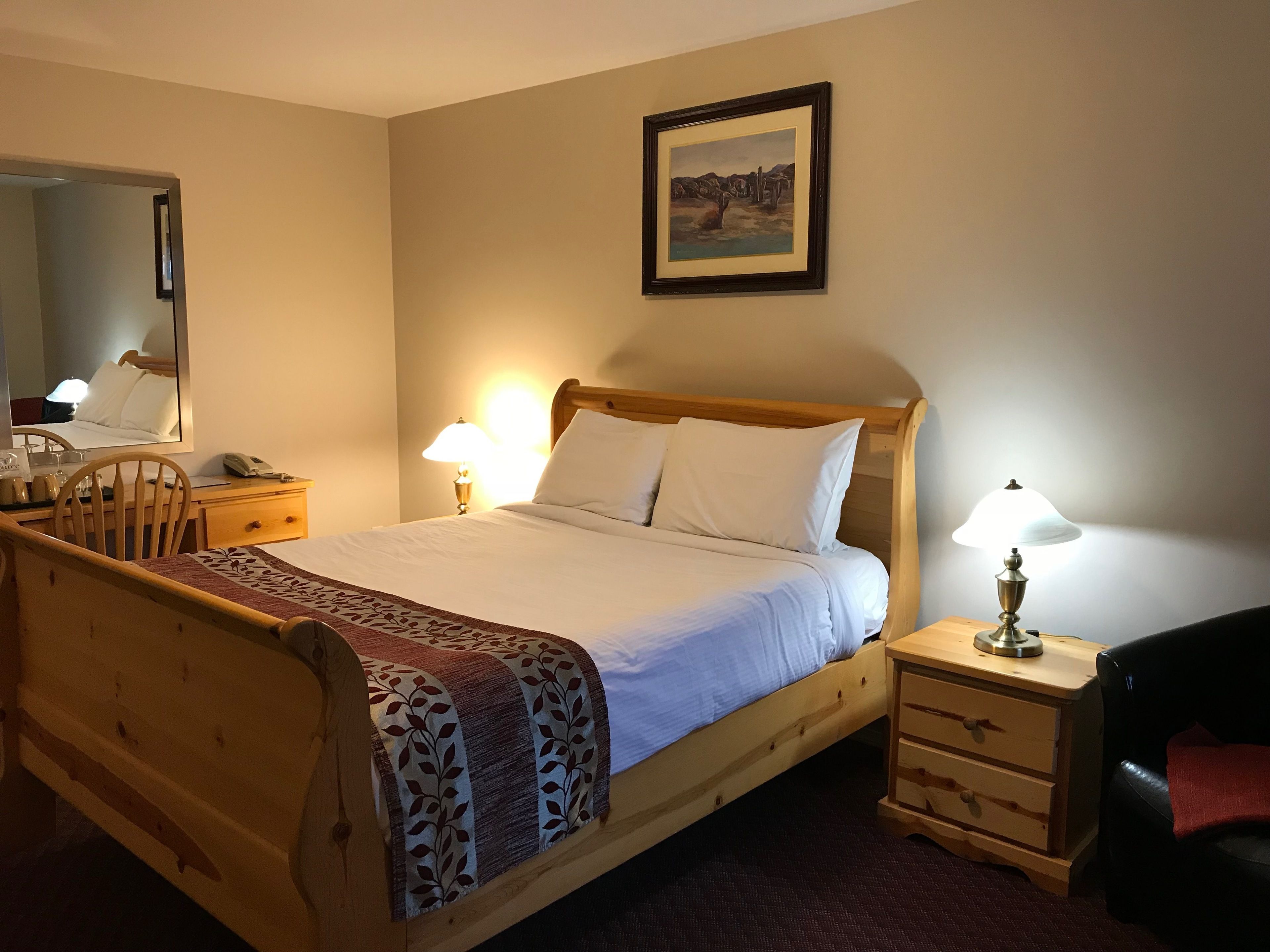 A neatly arranged bedroom with a wooden bed, bedside tables, a mirror, and a framed picture on the wall.