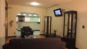Un hall de hotel con un sofá de cuero, un televisor en la pared y un mostrador de recepción.