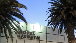 Exterior del HOTEL LIZBETH con cielo despejado y palmeras.