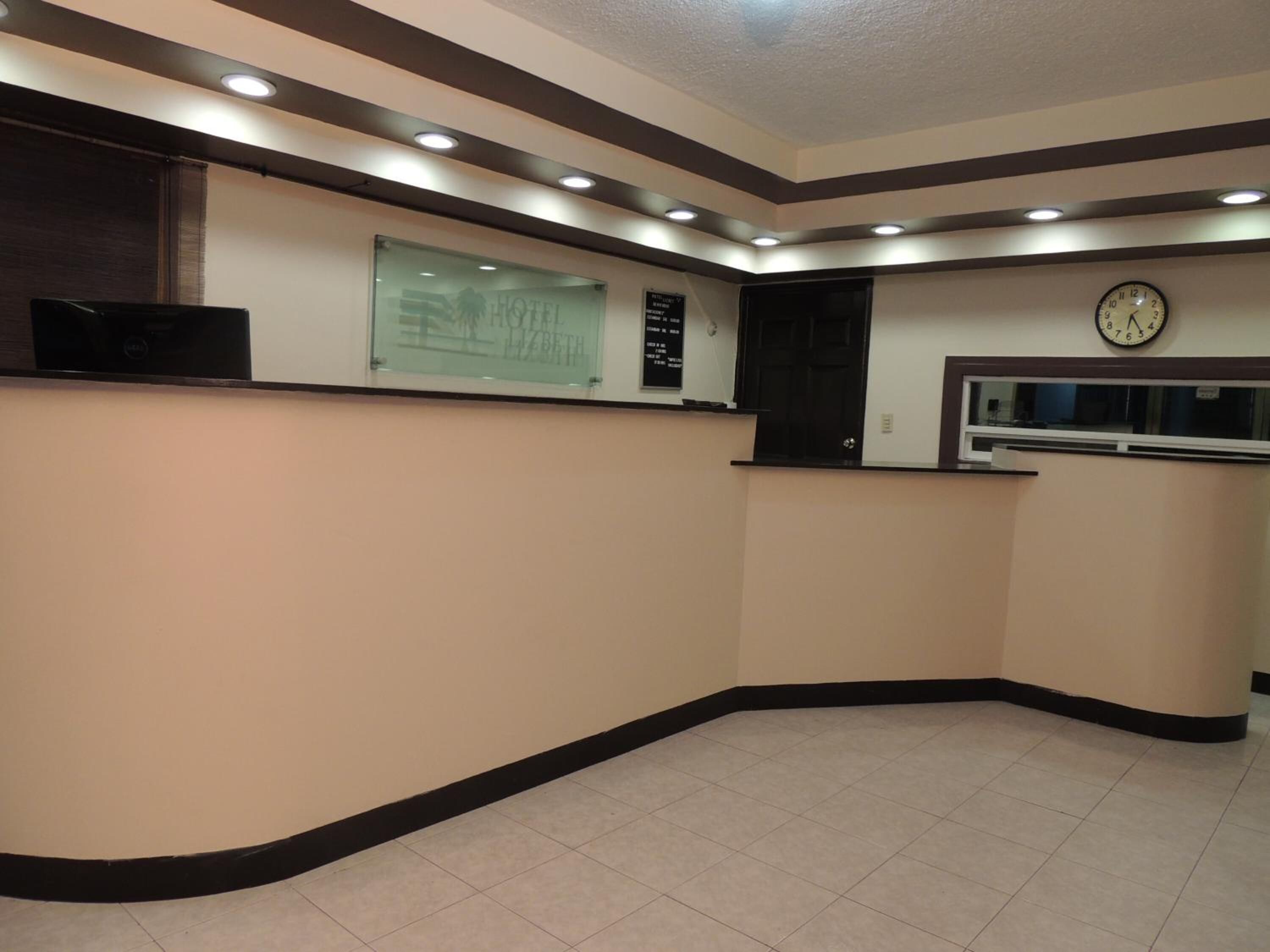 Zona de recepción de un hotel con un escaparate de vidrio, un reloj y un televisor de pantalla plana.