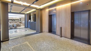 A modern lobby with a marble floor, wooden paneling, and a reception desk. - East Dragon Hotel (Taipei)
