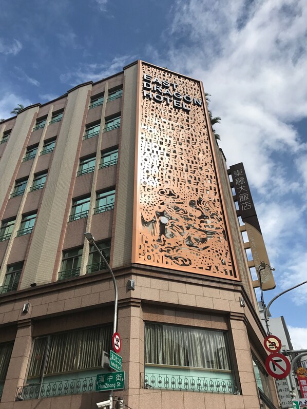 A hotel building with a large dragon design on the facade, multiple floors, and a sign indicating the hotel name.