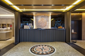 A reception area with a modern design, featuring a central decorative wall, a reception desk, and a patterned floor.