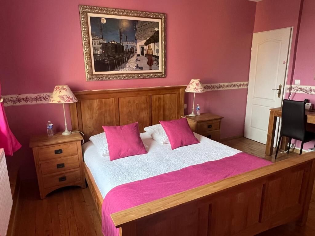 Un dormitorio con una cama de madera, dos mesitas de noche, un buró, un escritorio y una silla.