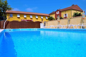 Une piscine avec un bâtiment jaune en arrière-plan, une enseigne de restaurant et un portail.
