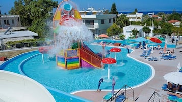 Un parc aquatique doté d’un grand toboggan aquatique, de plusieurs piscines et d’espaces de détente avec des parasols.