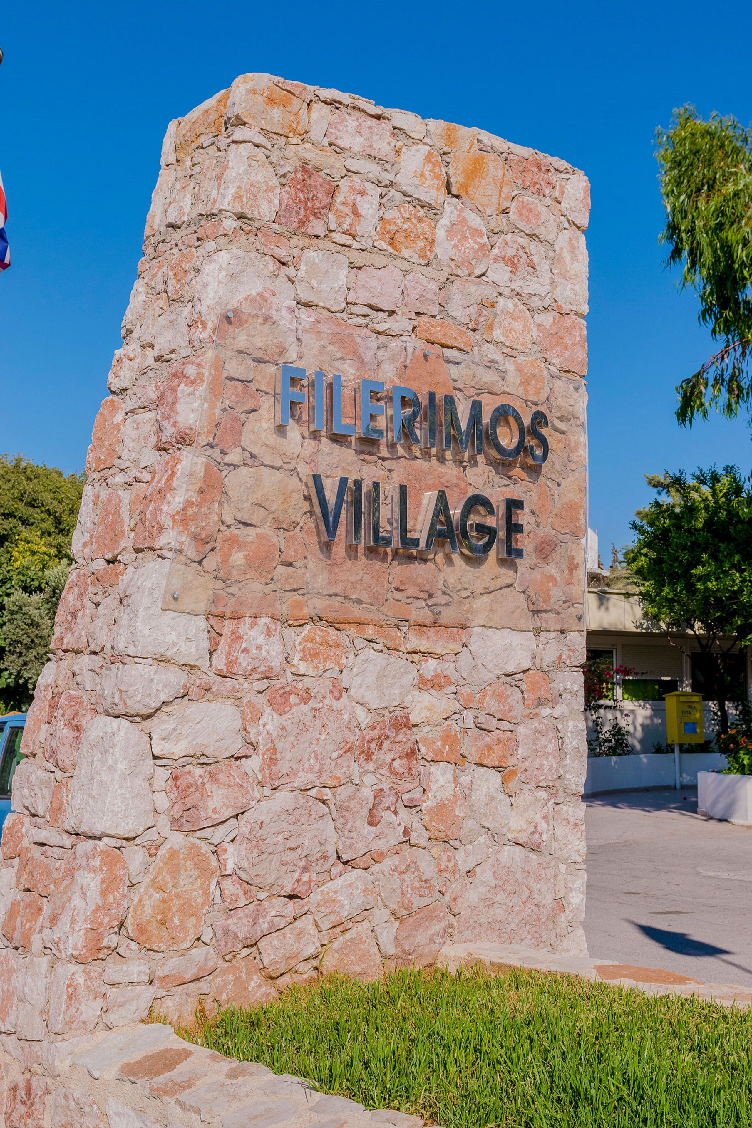 Un letrero de piedra con el texto 'Filerimos Village' que indica un lugar o nombre de propiedad.