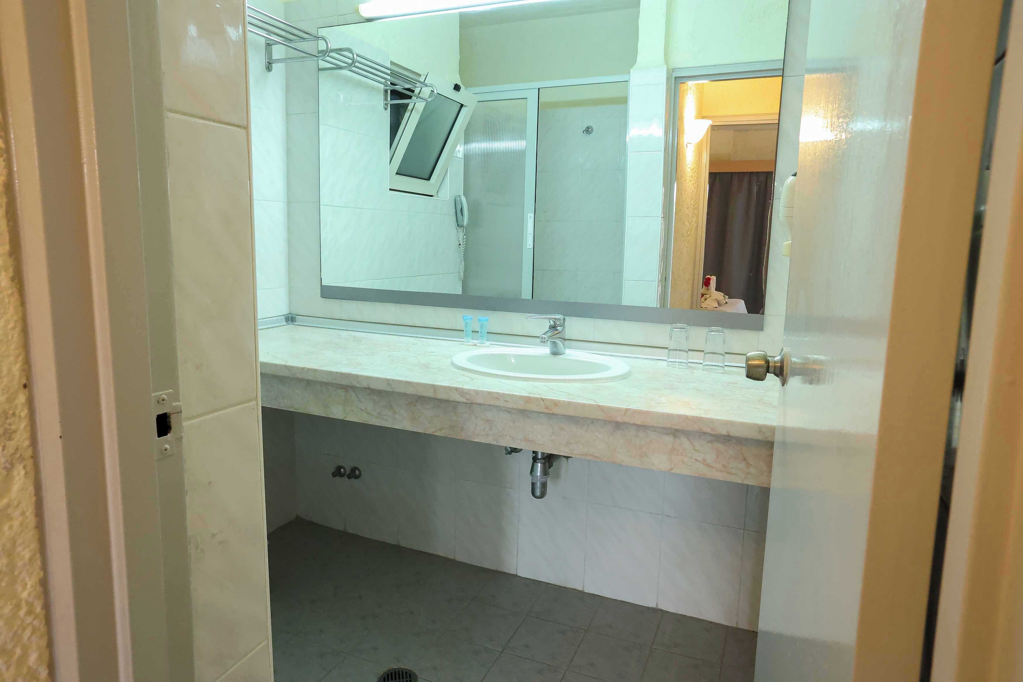 A bathroom with a sink, mirror, and shower stall.