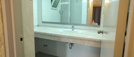 A bathroom with a sink, mirror, and shower stall.
