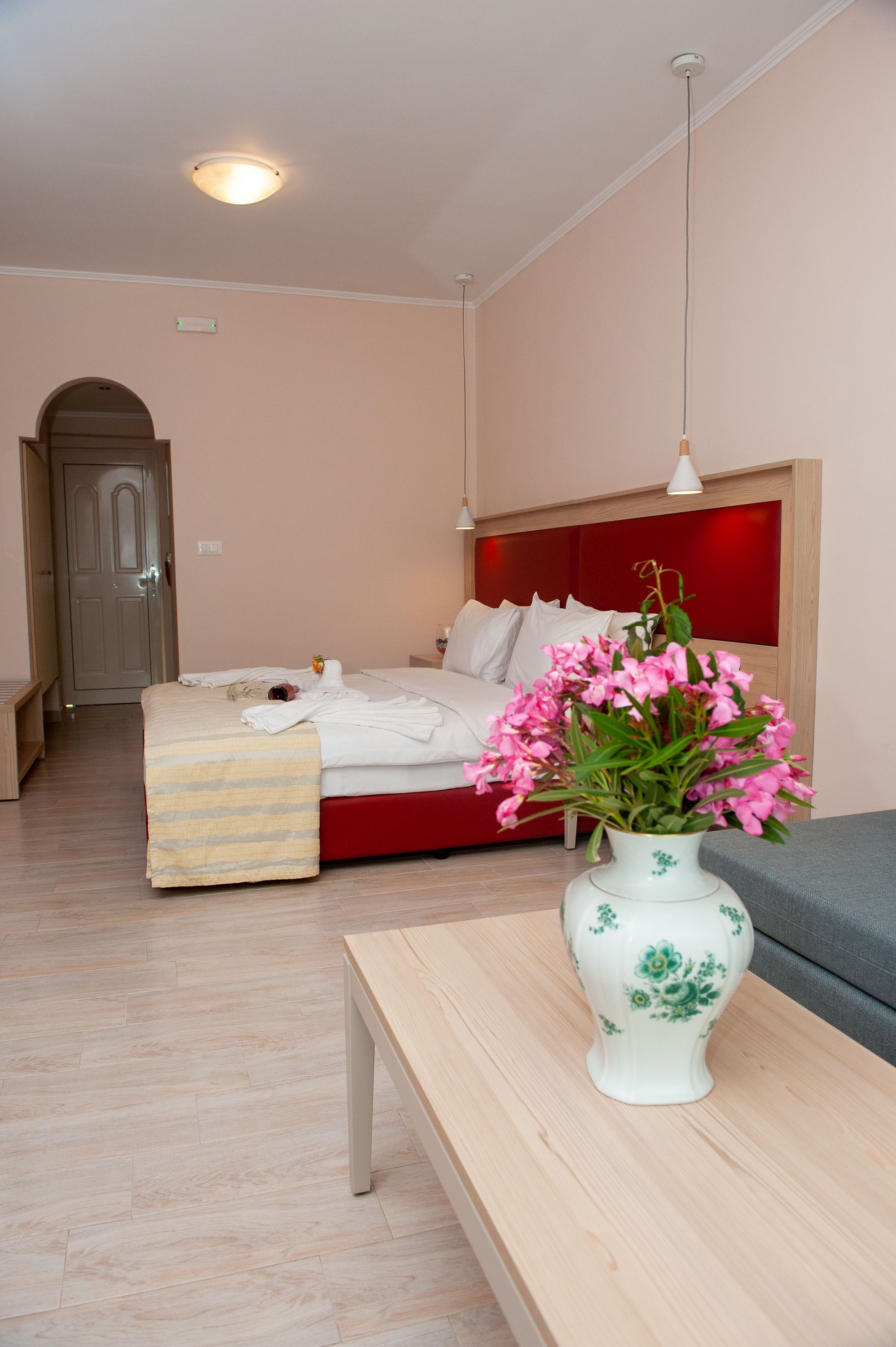 Une chambre à coucher avec un lit, une table de chevet et un vase de fleurs.