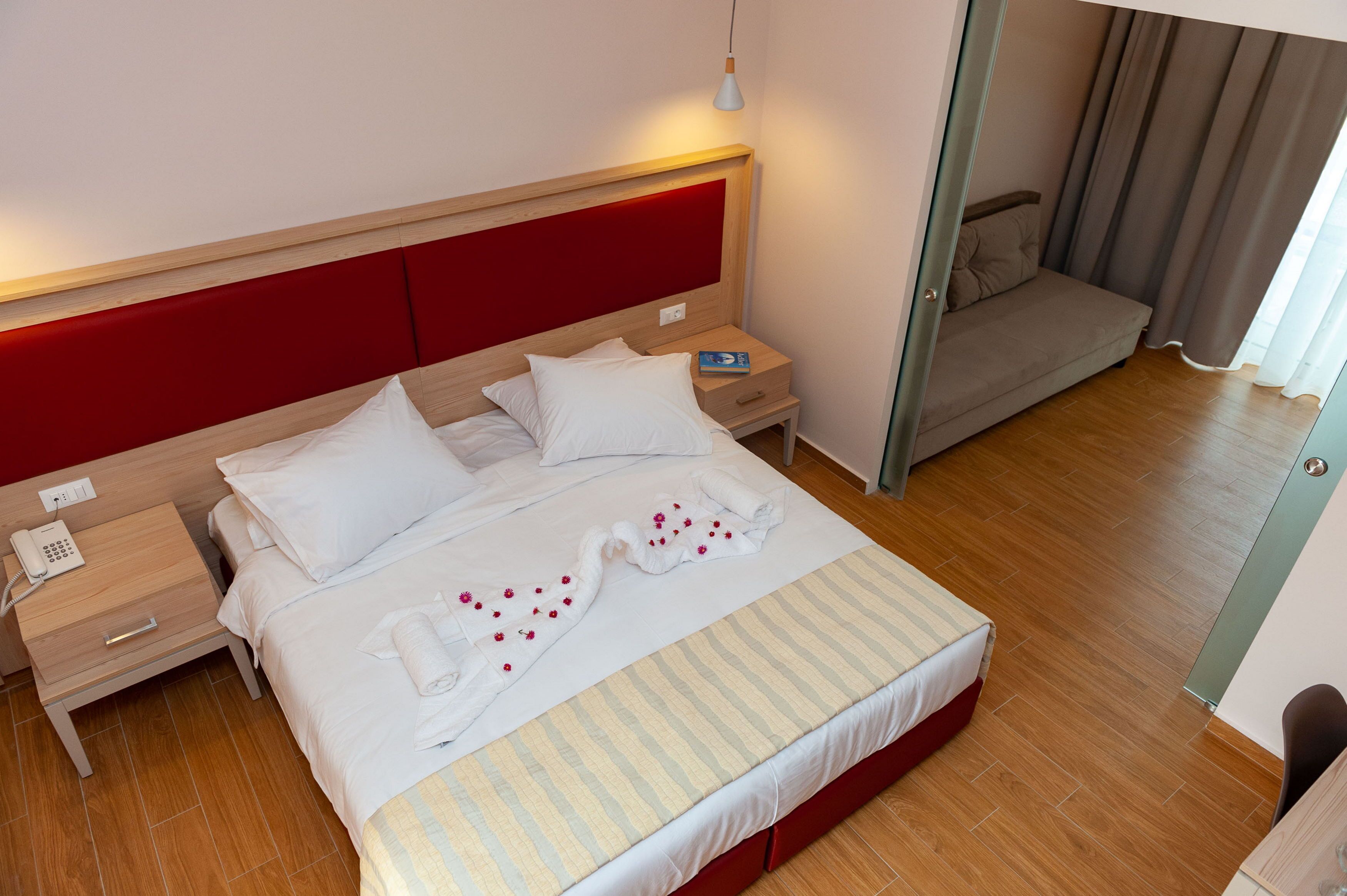 A neatly made bed with white linens and a striped blanket, a bedside table with a phone, and a small bedside lamp.