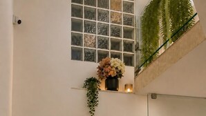 A staircase with glass railings, a potted plant, and a window with a view of greenery. - Esprit Hotel Budapest (Budapest)