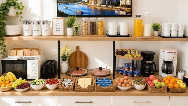 A breakfast buffet with various food items, a coffee machine, and a television displaying a cityscape. - Esprit Hotel Budapest (Budapest)