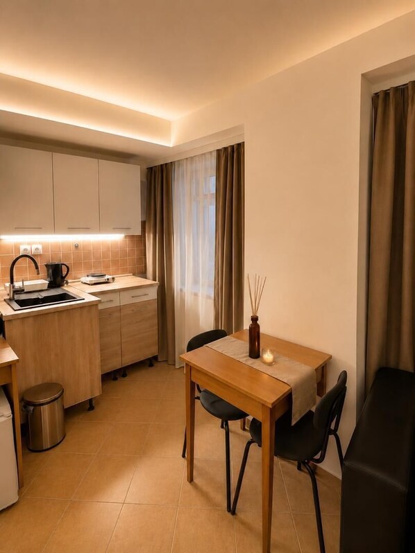 Una cocina compacta con comedor, que incluye una mesa, sillas y un pequeño cubo de basura.