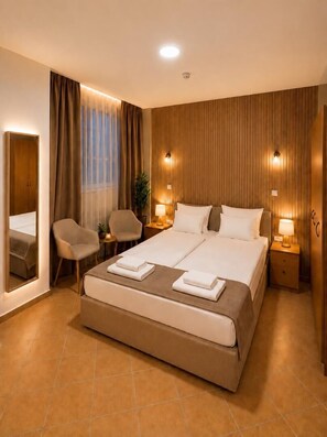 A hotel room with a large bed, two bedside tables, a chair, a mirror, and a window with curtains. - Esprit Hotel Budapest (Budapest)