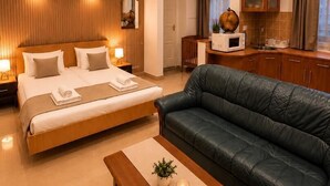 A modern hotel room with a large bed, a leather sofa, a wooden coffee table, and a kitchen area. - Esprit Hotel Budapest (Budapest)